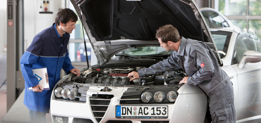 Ein Mechaniker und ein Prüfer begutachten ein Auto in einer Kfz-Werkstatt.