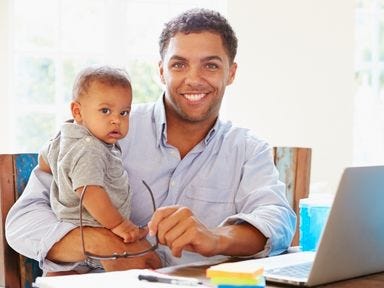 Erfolgreich nach der Elternzeit mit einer Online-Weiterbildung. Vater mit Kind nimmt an Online-Weiterbildung teil.