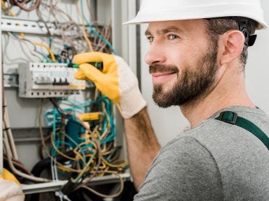 Ein Elektroniker arbeitet und prüft an einem Schaltschrank