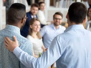 Erfolgreiche Qualifizierung dank finanzieller Unterstützung (Qualifizierungschancengesetz) Zwei Männer stehen freundschaftlich vor einer Gruppe.