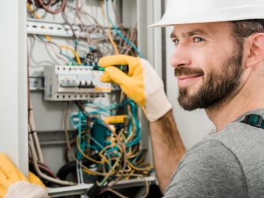 Ein Elektriker prüft Schaltpläne und installiert elektrische Anlagen auf einer Baustelle.
