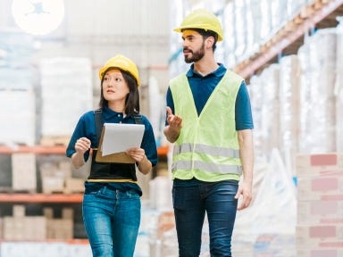 Lagerarbeiter überprüfen Waren und koordinieren Lieferungen in einer großen Lagerhalle.