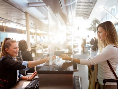 Servicekraft in der Fluggastabfertigung überreicht dem Gast ein Ticket.
