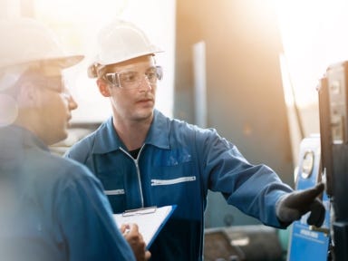 Ein Metallbauer bedient eine CNC-Maschine in einer Produktionshalle.