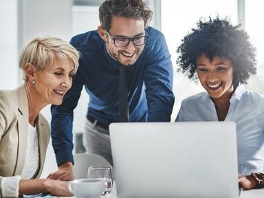 Ein diverses Team schaut gemeinsam auf den Laptop
