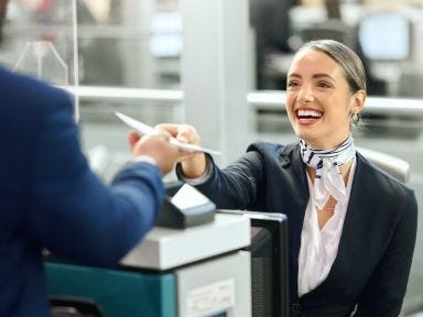 Eine Mitarbeiterin am Check-in Schalter überreicht einem Passaier seine Dokumente