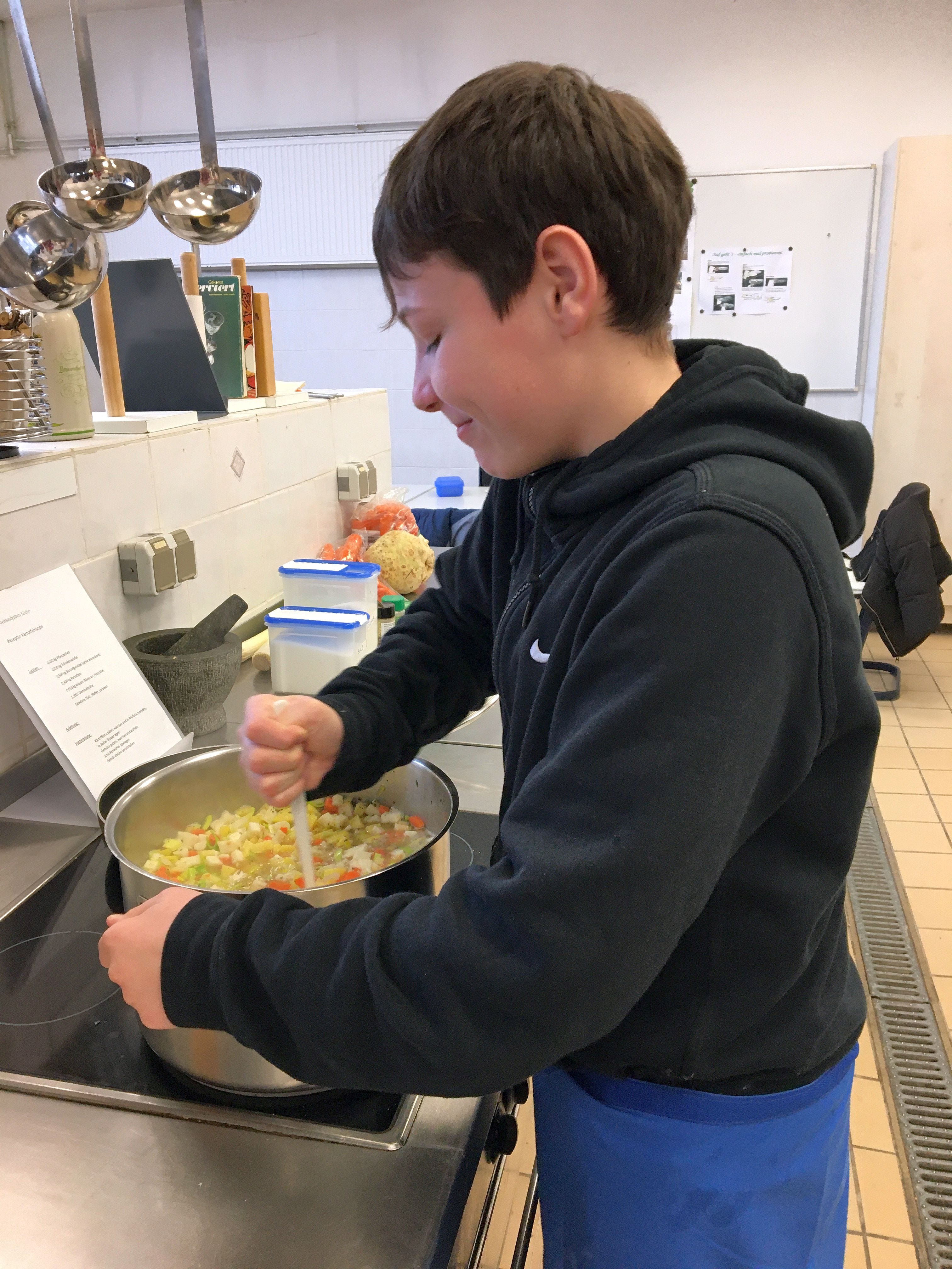 Sch&uuml;ler probiert Kochtechniken in der K&uuml;che aus