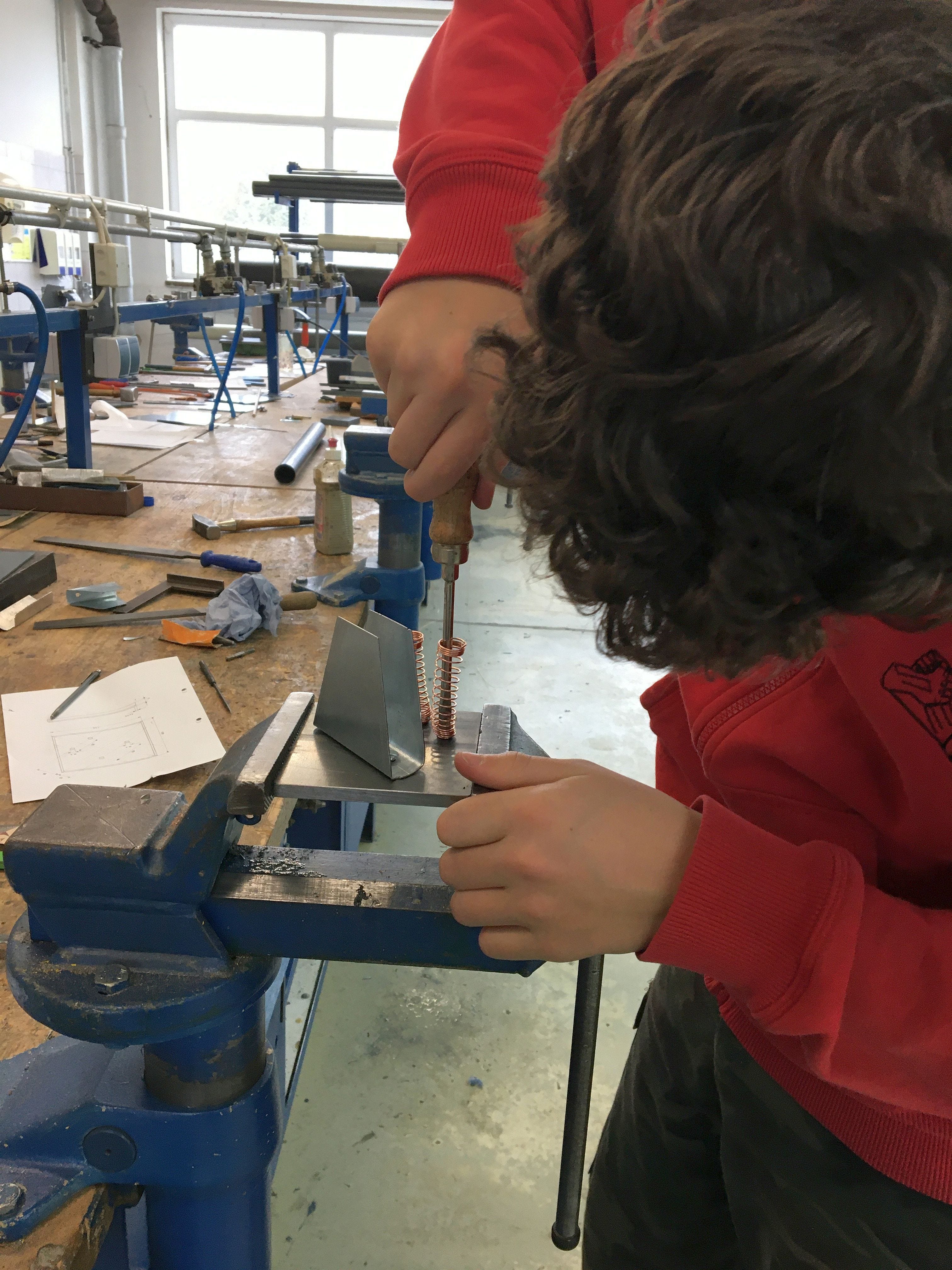 Ein Sch&uuml;ler bearbeitet ein Metallst&uuml;ck in der Werkstatt 