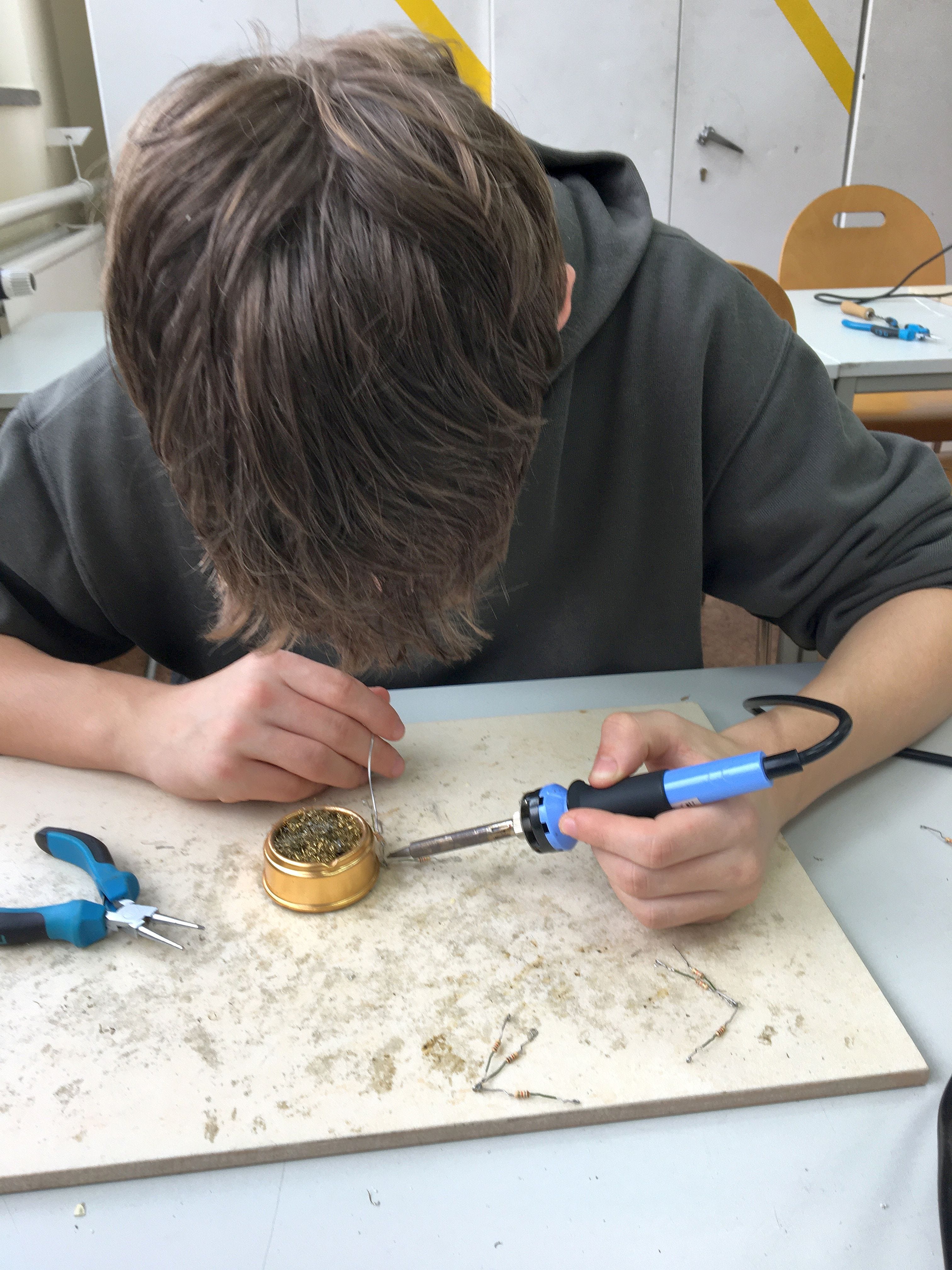 Ein Sch&uuml;ler l&ouml;tet ein paar Metallst&uuml;cke zusammen 
