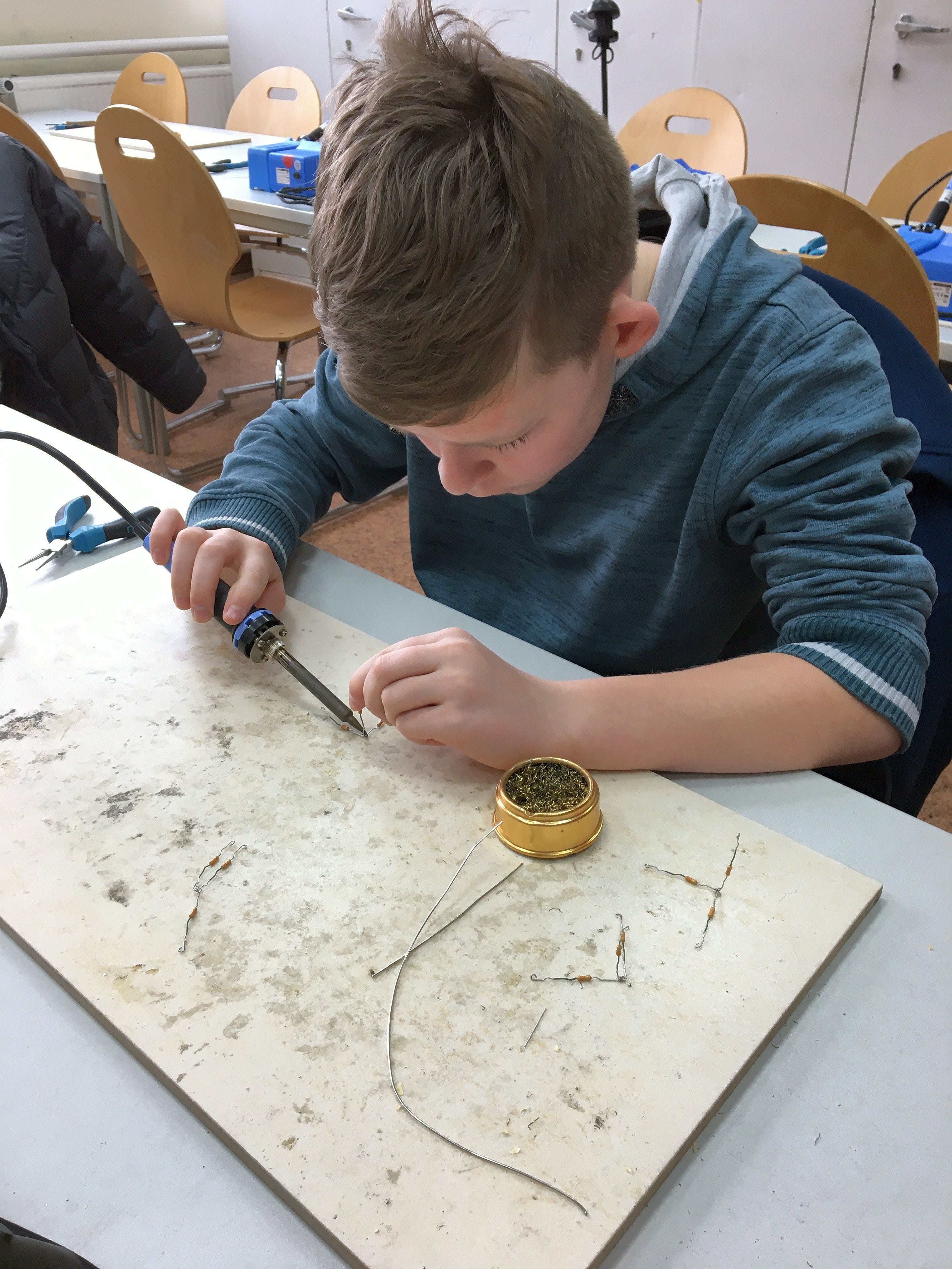 Ein Sch&uuml;ler l&ouml;tet Metalldrahte zusammen
