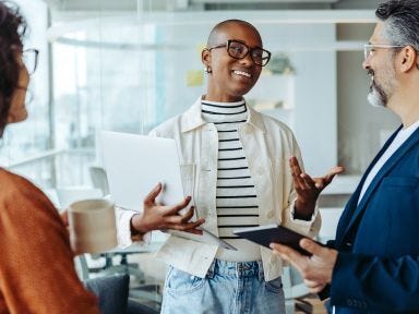 Zwei Frauen und ein Mann stehen in einem B&uuml;ro und besprechen die n&auml;chsten Schritte