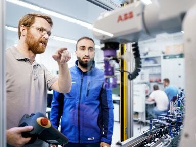 Im Rahmen der Verbundausbildung erkl&auml;rt ein Ausbilder einem Auszubildenden die Arbeitsweise einer Automatisierungsanlage. 