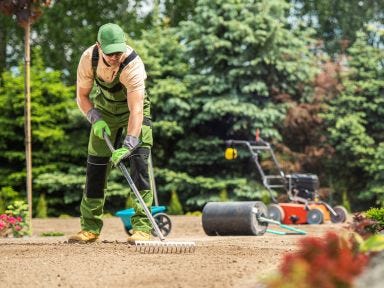 Ein Mann harkt bei seiner Weiterbildung zum Gartenlandschaftsbauer &uuml;ber der Erde 