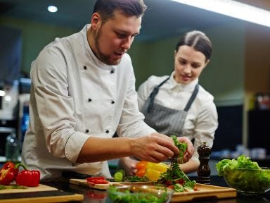 Ein Mann und eine Frau bereiten frisches Gemüse in einer Restaurantküche zu