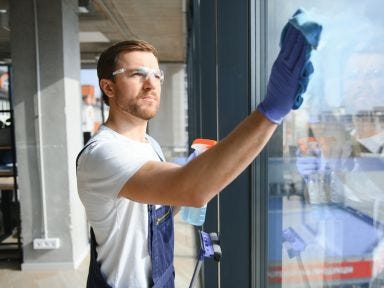 Ein Mann putzt ein gro&szlig;es B&uuml;rofenster