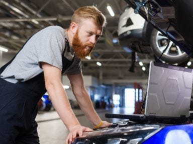 Ein Umsch&uuml;ler &uuml;berpr&uuml;ft einen Elektrowagen nach einem Wartungs- bzw. Serviceplan