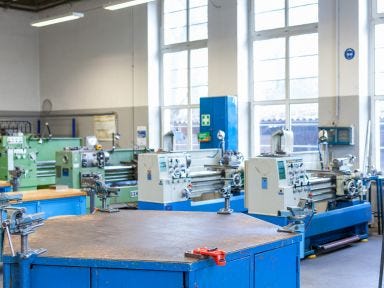 Eine Werkbank steht im Vordergrund und im Hintergrund stehen Drehmaschinen in einer Metallwekstatt