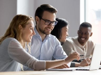 Zwei junge Frauen und zwei junge M&auml;nner sitzen ineinem B&uuml;ro und besprechen eine Aufgabe 