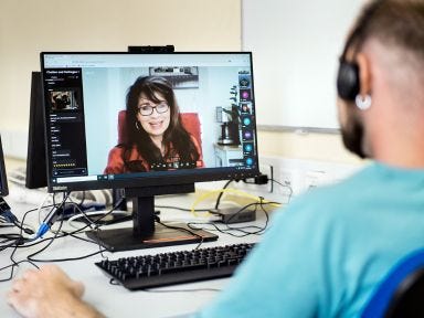 Eine Dozentin ist auf einem PC Bildschirm erkennbar und ein Teilnehmer sitzt vor dem Rechner mit Kopfh&ouml;rern