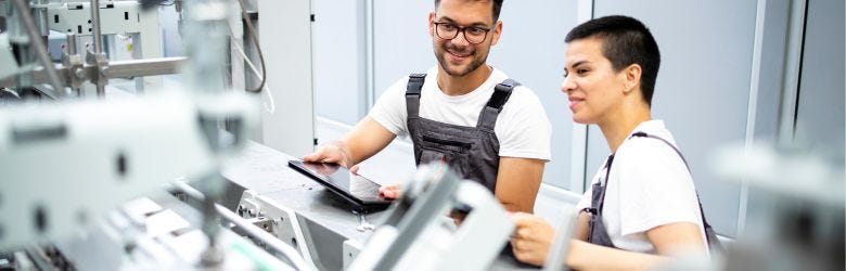 Ein Mann und eine Frau überprüfen die Maschinen in der Produktionsstätte. Ein Mann und eine Frau überprüfen die Maschinen in der Produktionsstätte.