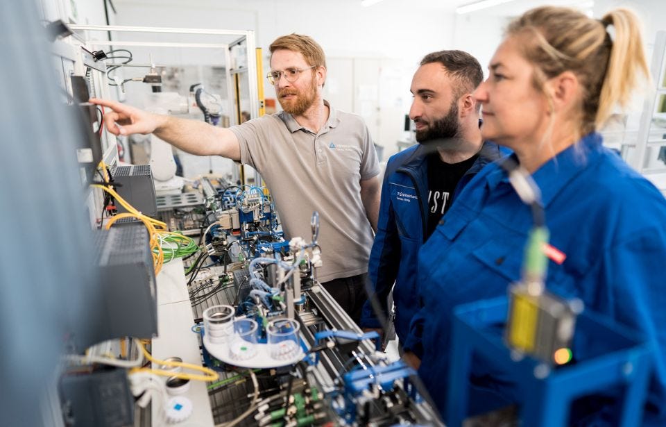 Ausbilderr erkl&auml;rt die Elektronik einer Automatisierungsanlage 