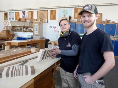 Zwei Umschüler stehen an einer Werkbank in einer Holzwerkstatt