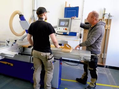 Ein Ausbilder erklärt einem Umschüler das Verfahren an einer Maschine