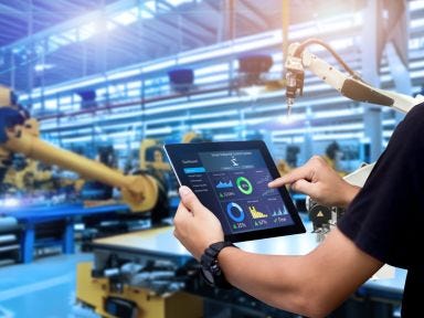 Mitarbeiter überprüft die technischen Einstellungen der Produktionsanlage an einem Tablet.